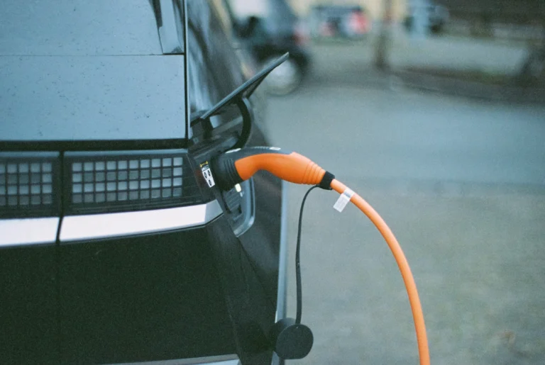 Close-up of an electric car charging with an orange cable.