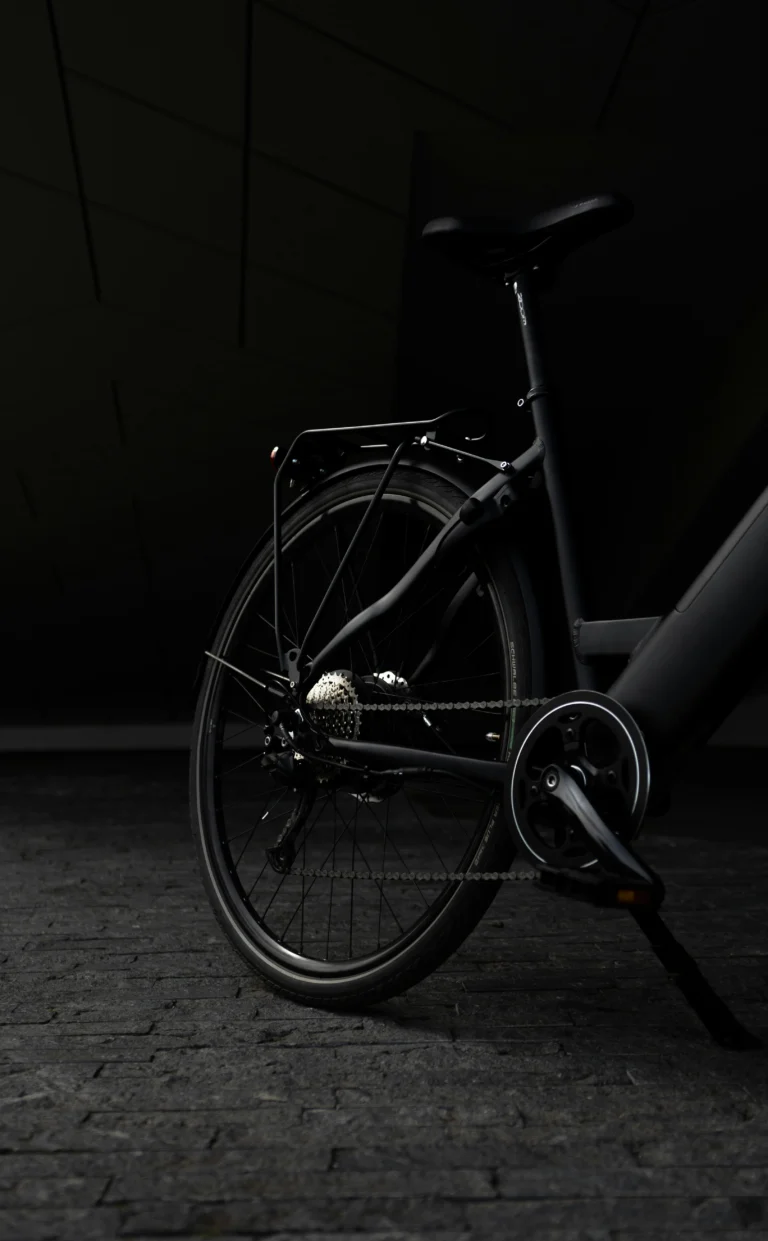 Close-up of a black bicycle’s rear wheel and drivetrain in low light.