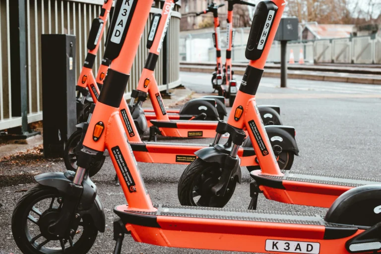 Bright orange electric scooters parked in a row on a street.