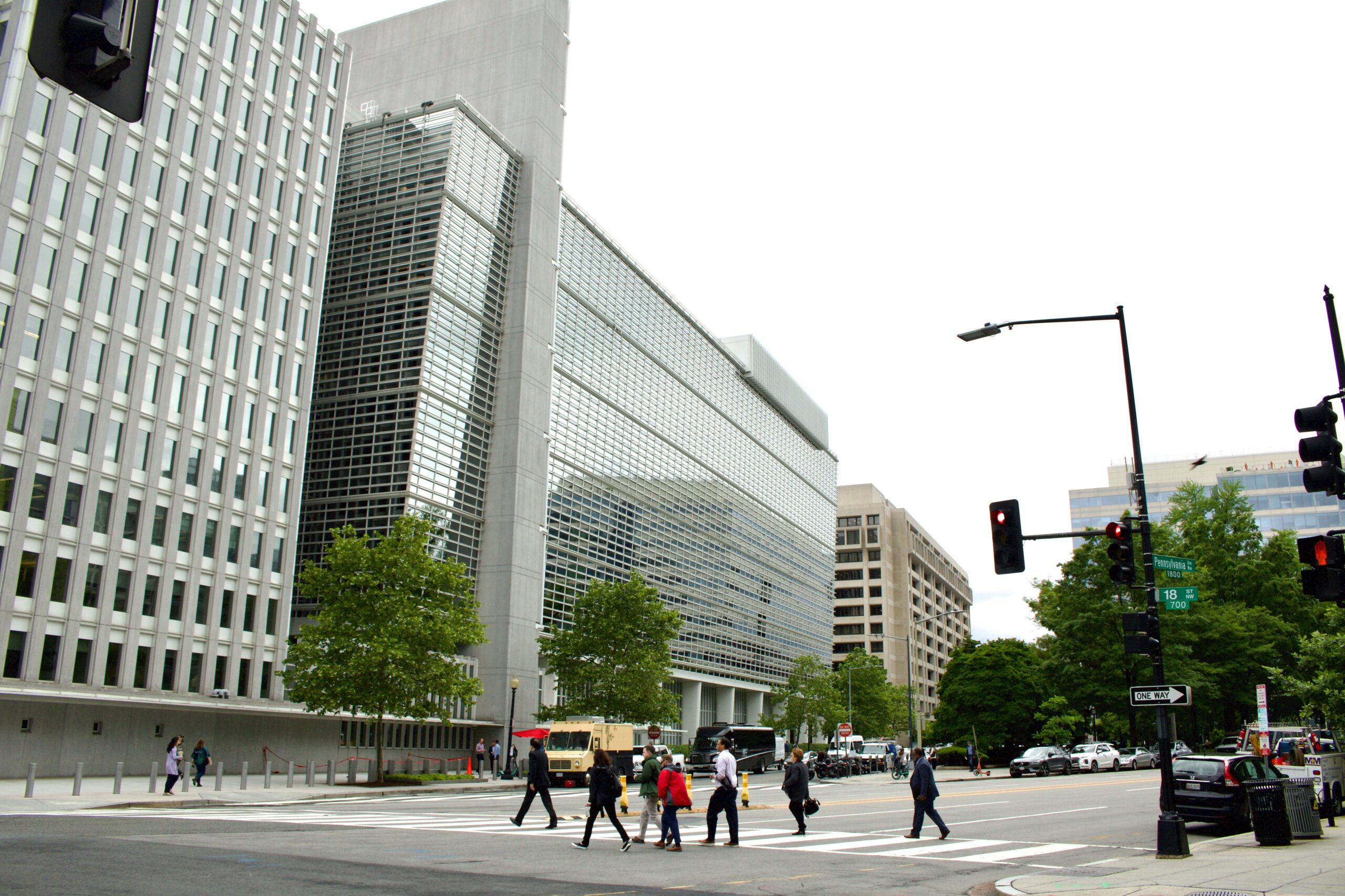 People crossing a street near modern glass office buildings.